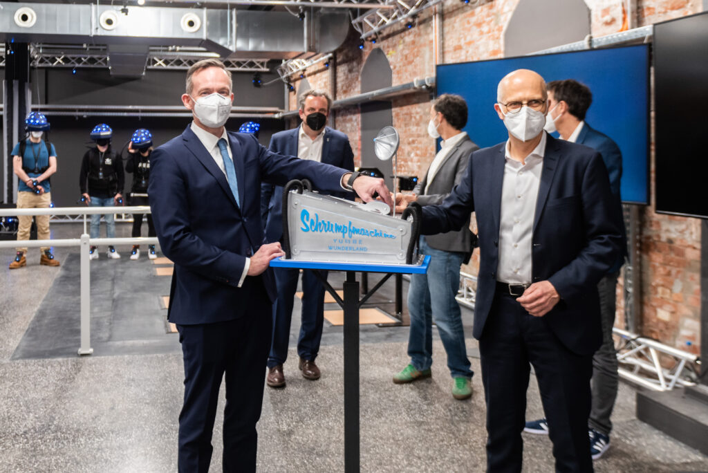 Dr. Volker Wissing und Dr. Peter Tschentscher legen den Hebel um für die ersten Gäste von YULLBE WUNDERLAND (im Hintergrund)